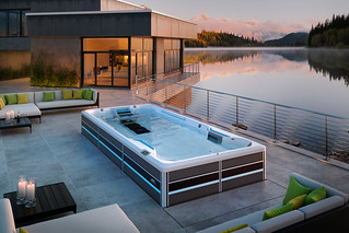endless pools swim spa e series sunken into concrete patio behind a modern style dimly lit home on a lake