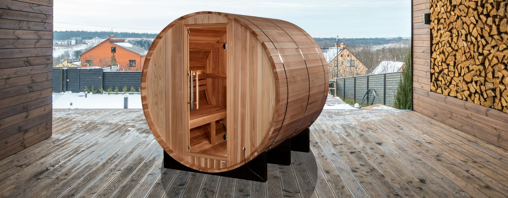 Cedar barrel sauna on a covered deck overlooking a snowy neighborhood